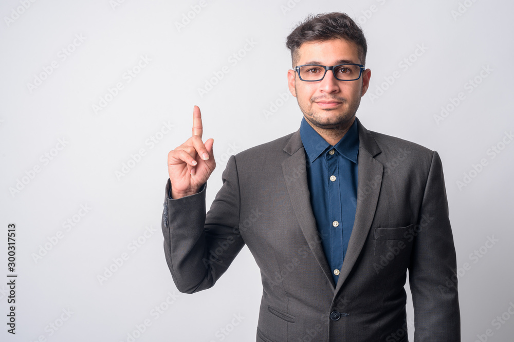 Portrait of young Persian businessman in suit pointing up Portrait of young Persian businessman in suit pointing up