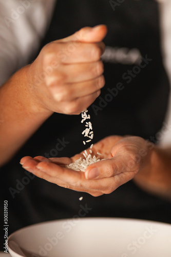 Rice grains fall from one hand to another.