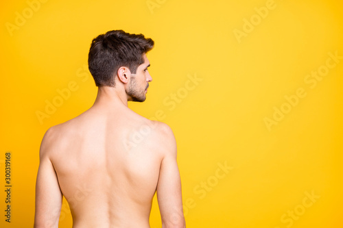 Rear behind profile view photo of handsome guy showing perfect spine muscles looking seriously empty space naked isolated yellow color background photo