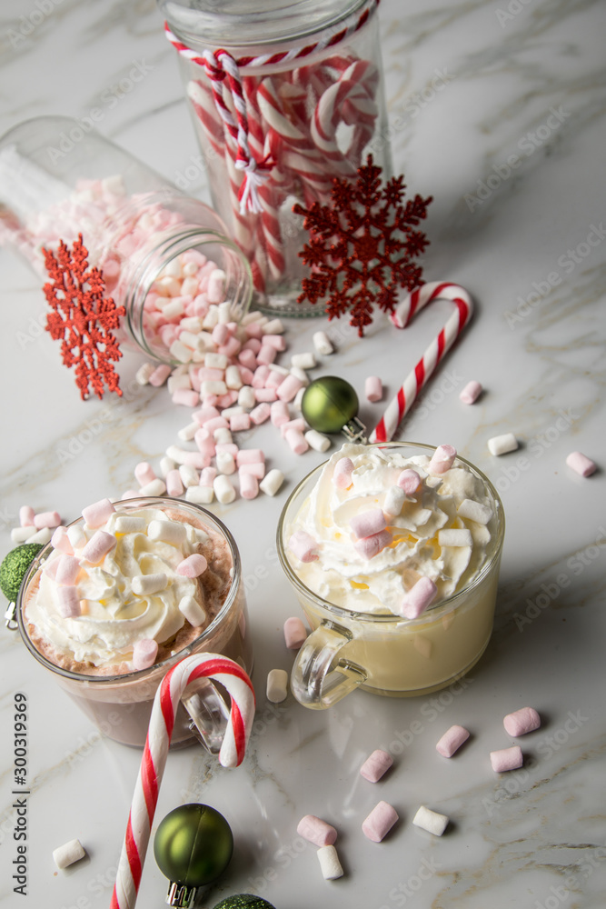 Heiße, dunkle Trinkschokolade zu Weihnachten mit Sahne, Marshmellows, Christbaumkugeln grün, Zuckerstangen, Glitzer Schneeflocken rot auf Marmor hell Hintergrund Heiße, dunkle Trinkschokolade zu Weihnachten mit Sahne, Marshmellows, Christbaumkugeln grün, Zuckerstangen, Glitzer Schneeflocken rot auf Marmor hell Hintergrund