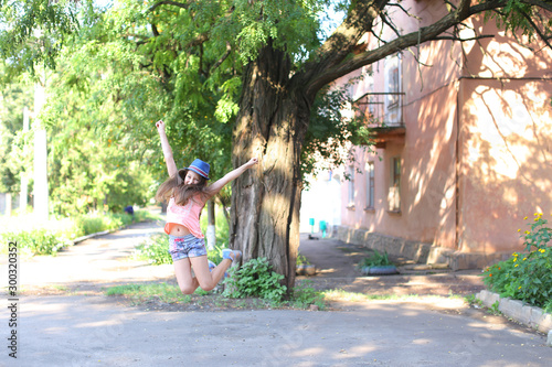 Pretty cute female girl child jumping and having fun in yard on street. photo