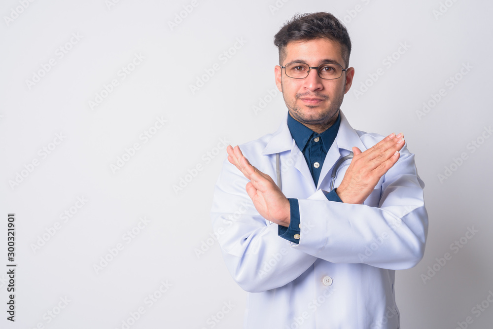 Portrait of serious young Persian man doctor with stop gesture Portrait of serious young Persian man doctor with stop gesture