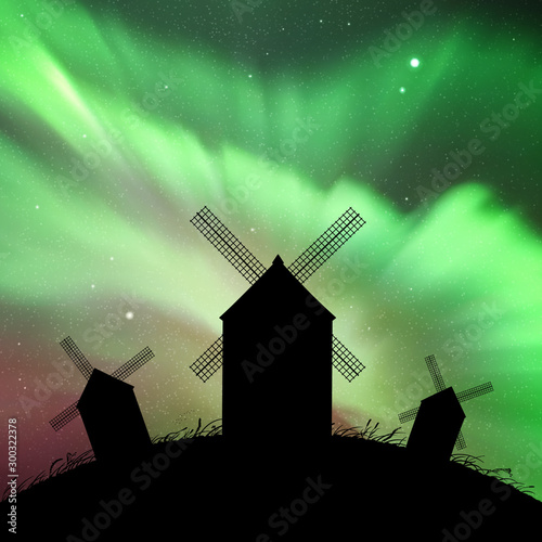 Windmills in field at night. Vector illustration with silhouettes of mills on hill. Summer rural landscape. Northern lights in starry sky. Colorful aurora borealis