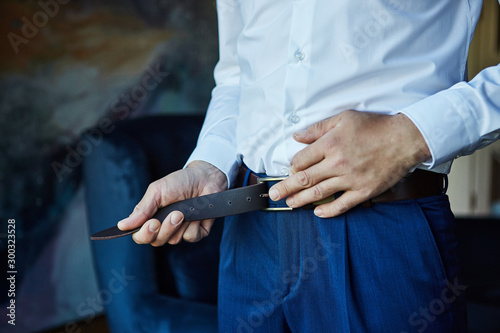 Businessman putting on a belt, fashion and clothing concept,groom getting ready in the morning before ceremony