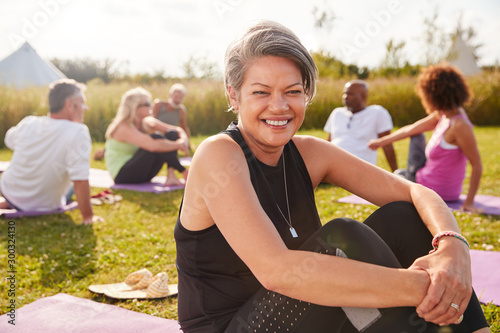 Portrait Of Mature Woman On Outdoor Yoga Retreat With Friends And Campsite In Background photo