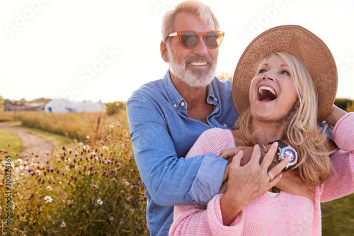 Loving Mature Couple In Countryside Hugging Against Flaring Sun photo