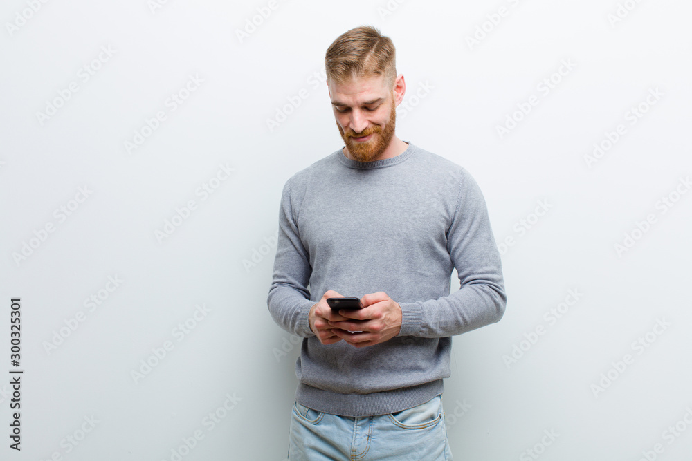 young red head man with a smart phone against white background - obrazy, fototapety, plakaty 