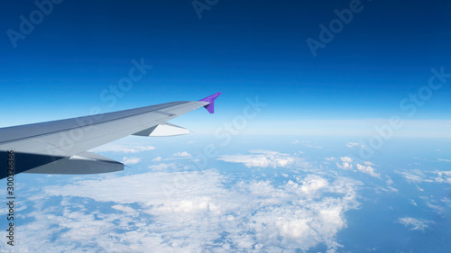 Wing of an airplane flying above the clouds with blue sky, aerial view from the window of the plane,airtransportation make your life easy for travel.