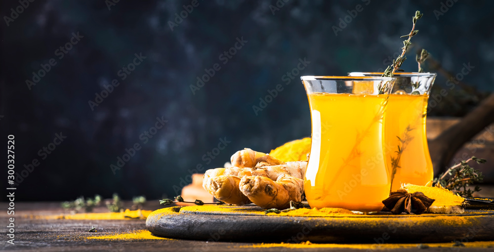 Healthy vegan turmeric golden tea with honey in glass cup on wooden tray. Herbal healing spicy tea - obrazy, fototapety, plakaty 