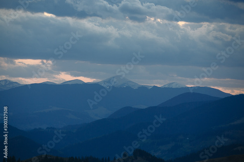 snow mountain peaks stick out on the horizon under the clouds © Andrii