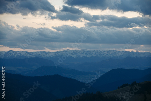 Fototapeta Naklejka Na Ścianę i Meble -  snow mountain peaks stick out on the horizon under the clouds