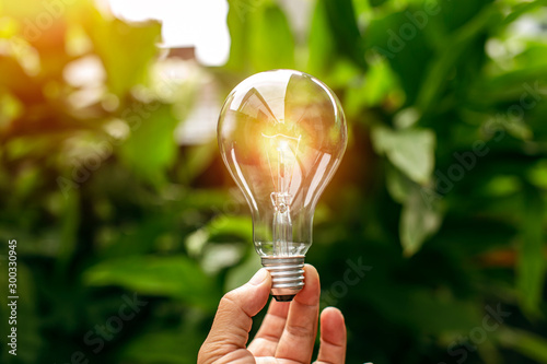 hand holding light bulb against nature, icons energy sources for renewable 