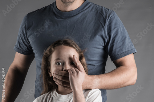 Male hands on little crying girl, concept of children exploitation.