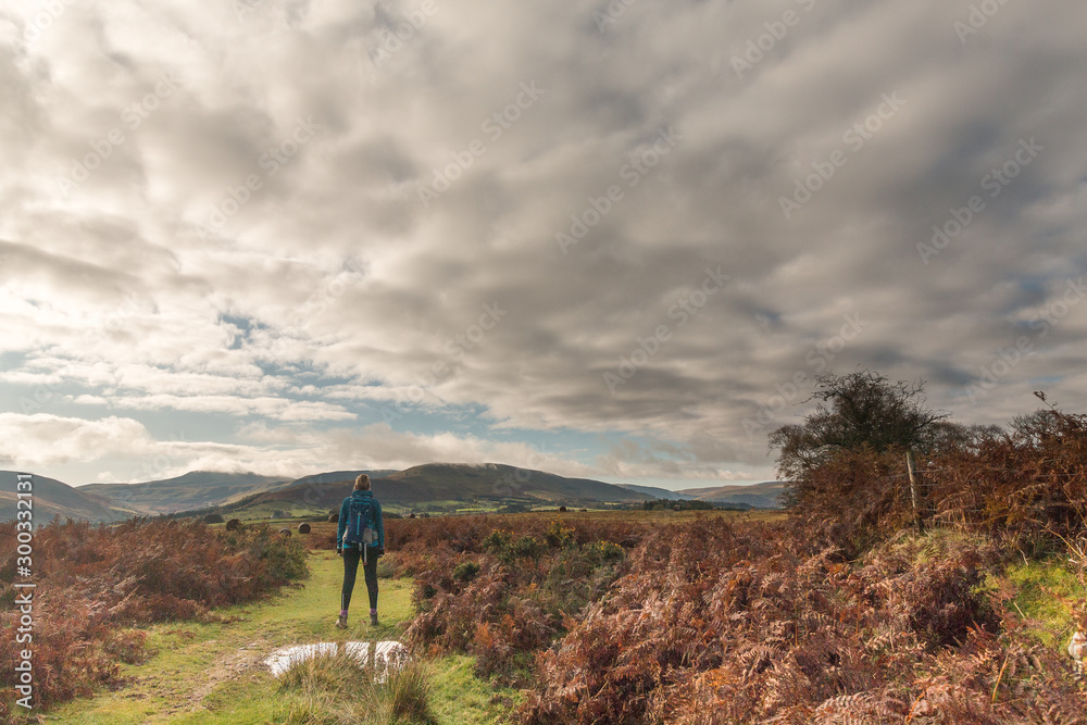 A woman hiking on a track in the mountains of the Brecon Beacons National park, Wales. November 2019.