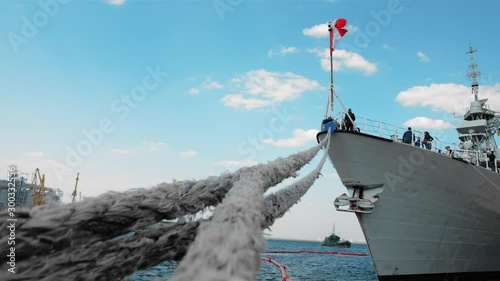 NATO warship with a Canadian flag is moored at the port. On board unidentified people. Close-up of ropes holding the ship anchored. The concept of ending the war.