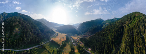 Wide aerial view of a camping site, recreation with a tent and parking for a motor home, camper van, sunrise summer, mountains and a river near the town of Predazzo, Trentino, Italy, Europe