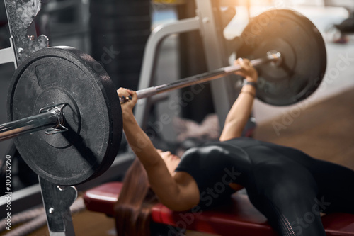 Canvas Print Close up of black iron barbell with heavy discs in hands of strong female weight
