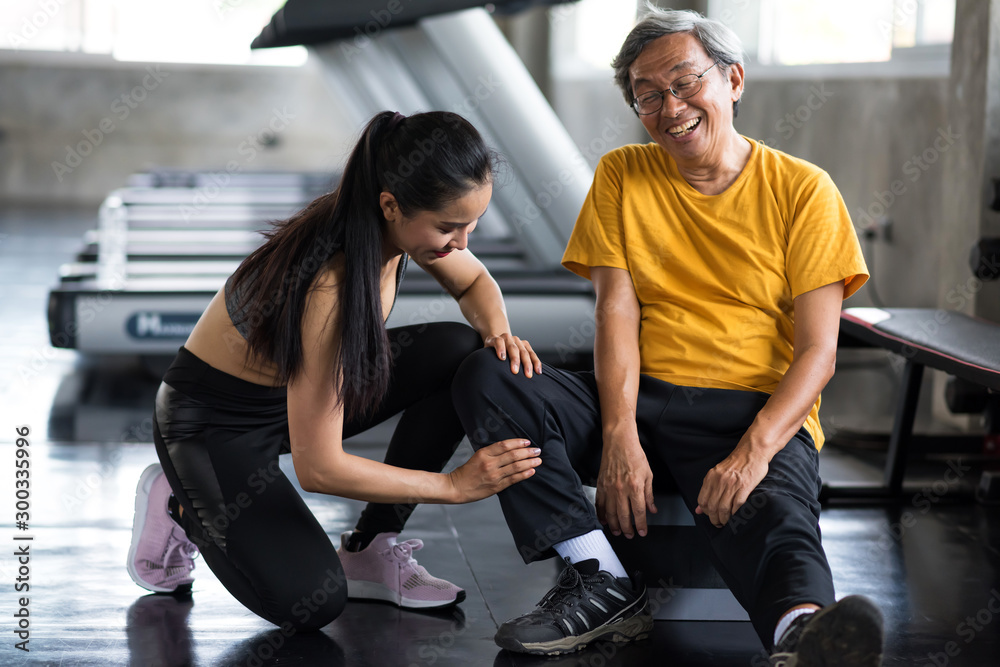 Old man massage leg by girl in gym Old man massage leg by girl in gym