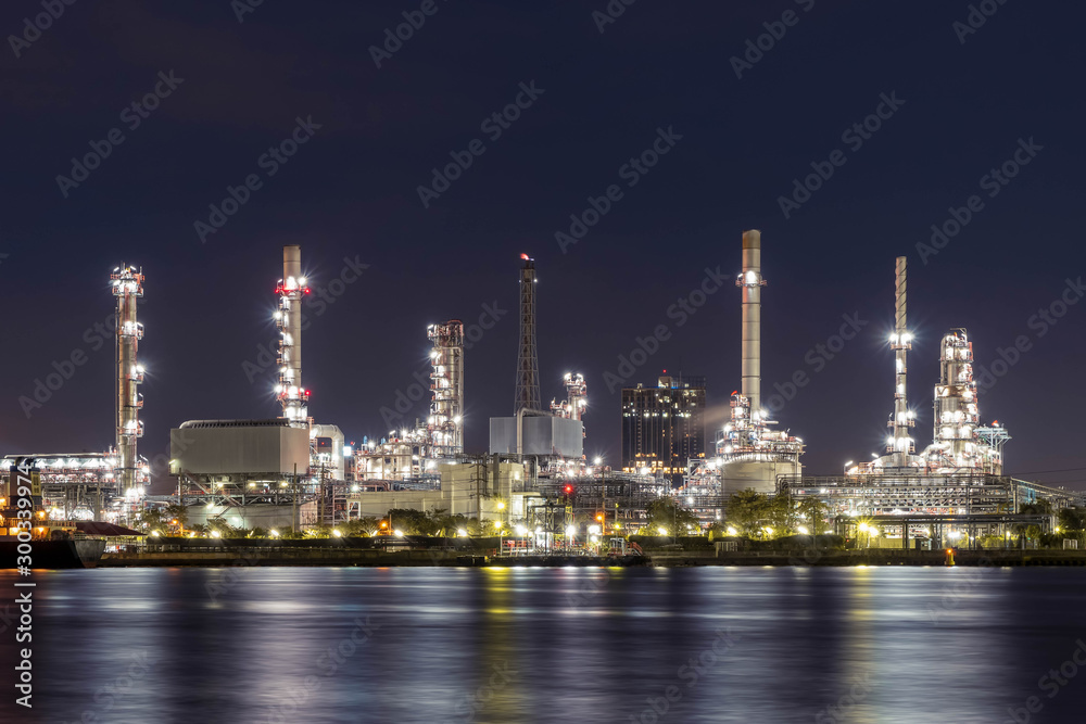 Oil refinery at night petrochemical and energy industry with refection on river