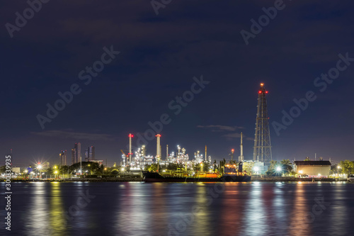 Oil refinery at night petrochemical and energy industry with refection on river