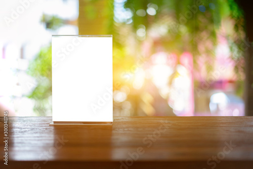 Mock up Label the blank menu frame in Bar restaurant ,Stand for booklets with white sheets paper acrylic tent card on wooden table cafeteria blurred background can inserting the text of the customer. photo