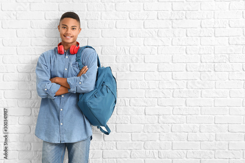 Portrait of African-American teenage schoolboy on brick background photo