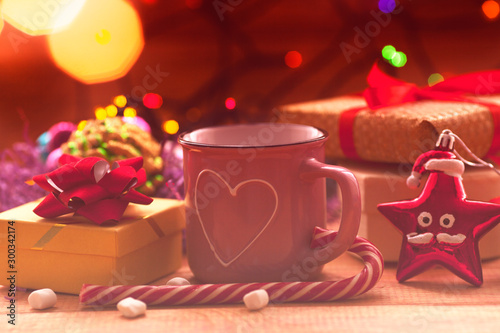 Christmas composition with the lights. Cup of coffee, beautiful toys, gifts and candy on the wooden background. New year background. Close up. Space for a text.