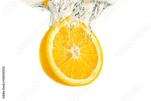 Fototapeta Naklejka Na Ścianę i Meble -  Orange half splashing into water and sinking isolated on white background. Citrus drink concept.
