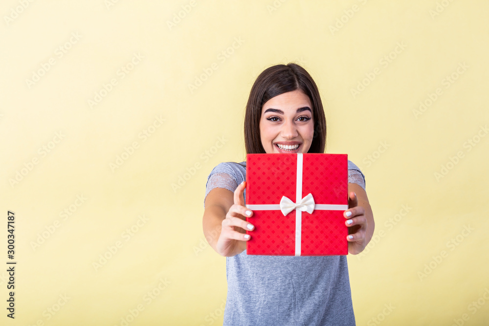 Portrait of nice attractive lovely sweet fascinating cheerful cheery girl holding in hands bow ribbon box isolated over yellow pastel background. Young woman hold gift in christmas style