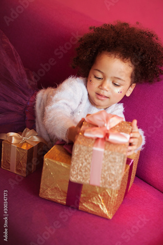 Cute little girl with a lot of gift boxes sitting on sofa