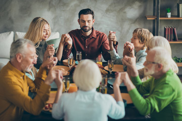 Big family father mother mature grandparents kids small girl boy gather sit table enjoy november feast meal pray celebrate thanksgiving day hold hands in house