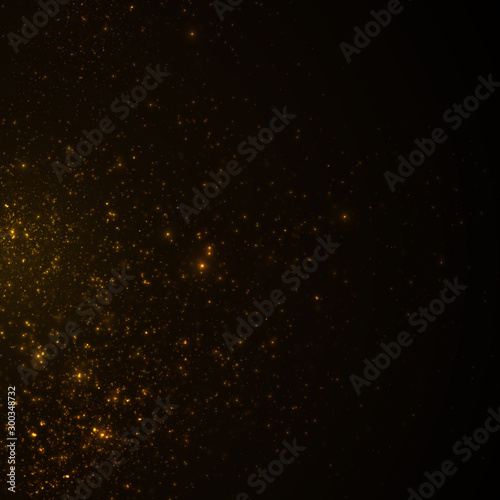 Golden particles, sparkling glitter dust on dark background.