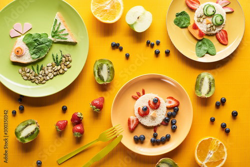 top view of plates with fancy animals made of food on colorful orange background