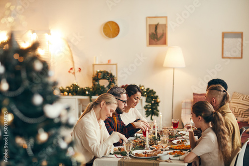Fotografia Wide angle view at modern young people celebrating Christmas sitting at dinner t