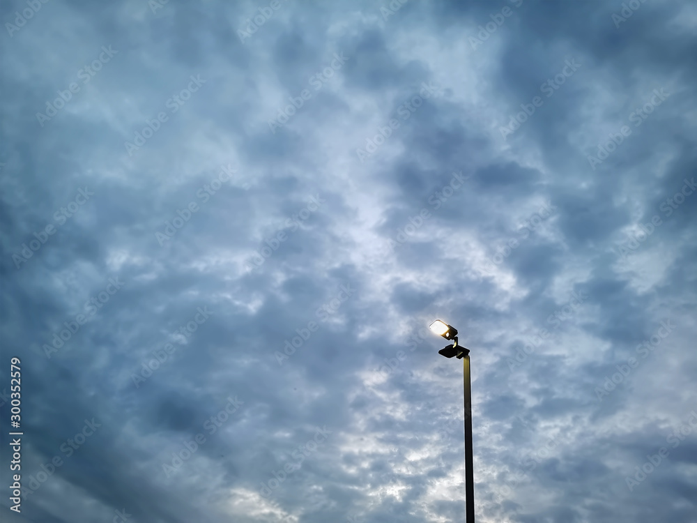 Low Angle View of Illuminated  Lighting Post Against Dark Stormy Sky