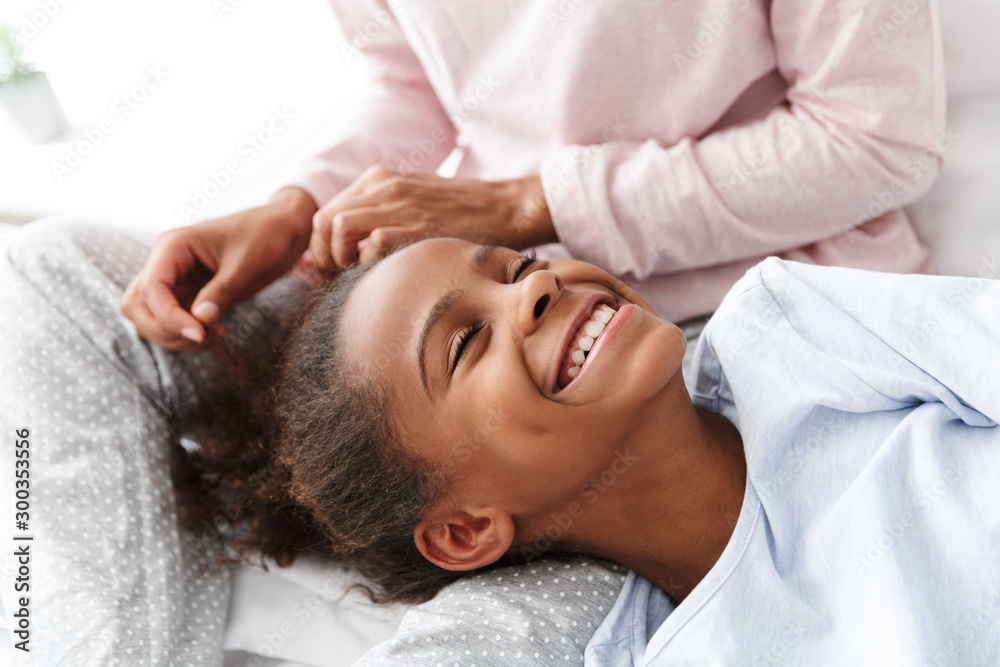 Image of young woman and her african american daughter on sofa at home Image of young woman and her african american daughter on sofa at home