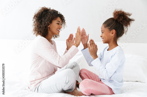 Image of african american woman and her daughter clapping their hands