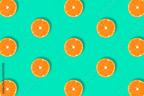 Fruit pattern of fresh mandarin slices on blue background.