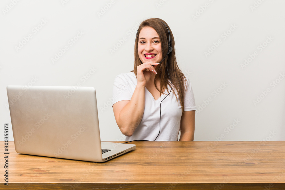 Young telemarketer woman smiling happy and confident, touching chin with hand.