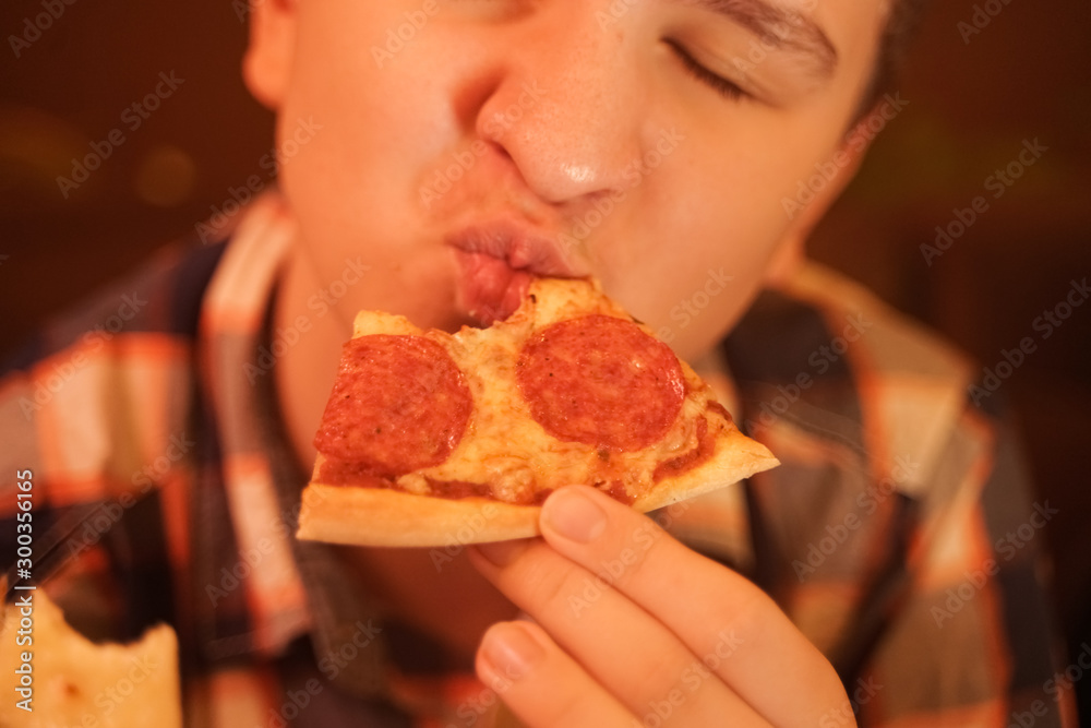 teen boy eats pizza and enjoys it, closeup enjoying and savoring.