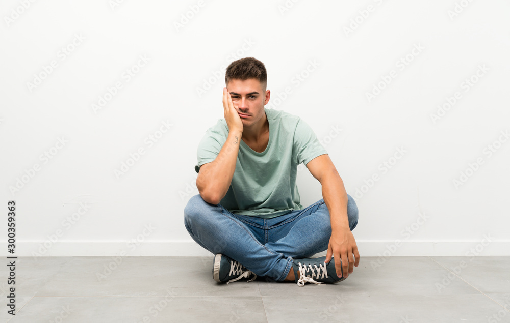 Young handsome man sitting on the floor unhappy and frustrated Young handsome man sitting on the floor unhappy and frustrated