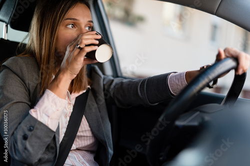 Businesswoman drinking coffee while driving a car.