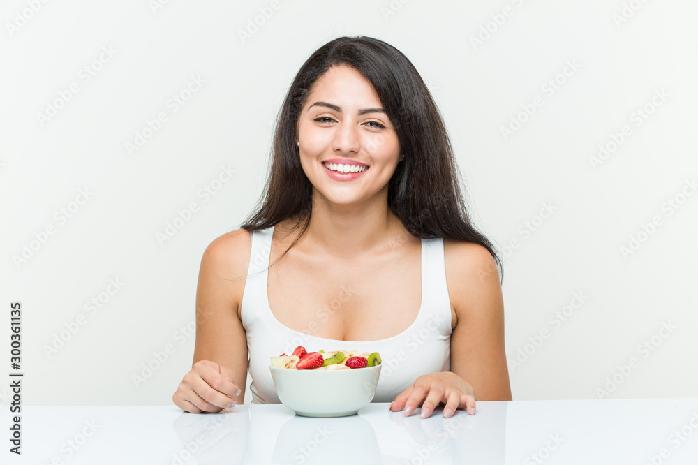 Young hispanic woman eating a fruit bowl happy, smiling and cheerful. Young hispanic woman eating a fruit bowl happy, smiling and cheerful.