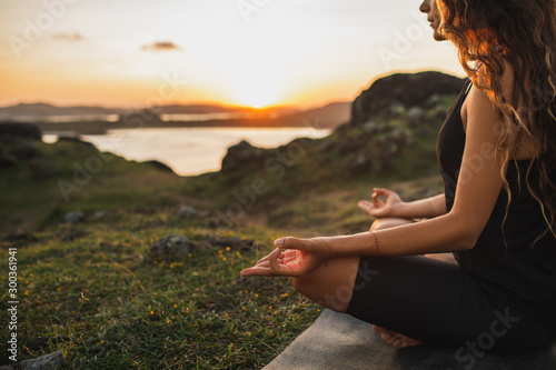 Healthy Lifestyle and Yoga Concept. Close-up hands. Woman do yoga outdoors at sunrise in lotus position. Woman exercising and meditating in morning. Nature background.