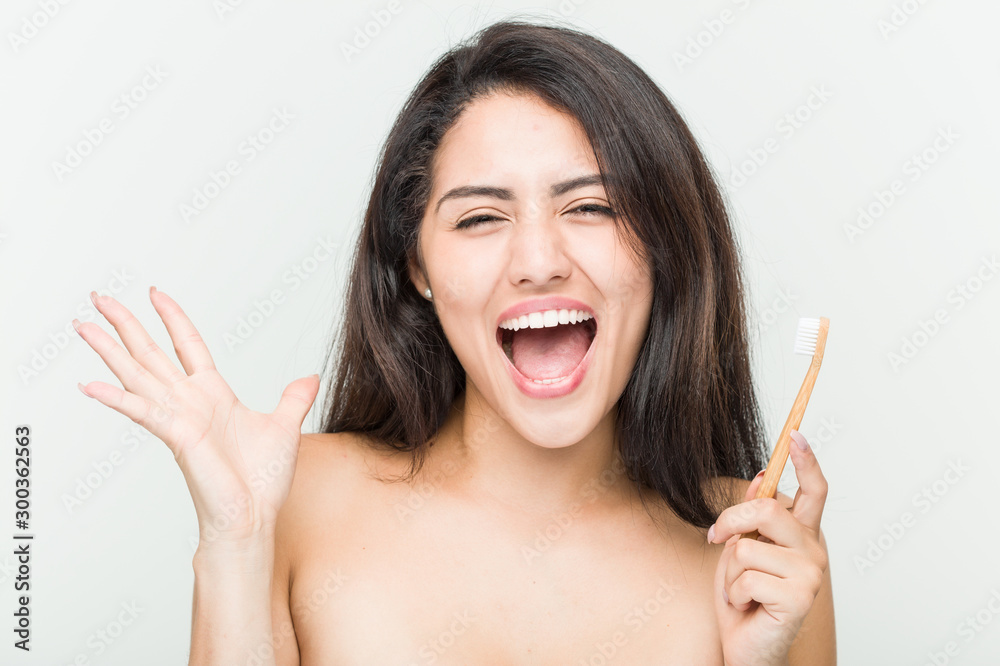 Young hispanic woman holding a toothbrush celebrating a victory or success Young hispanic woman holding a toothbrush celebrating a victory or success