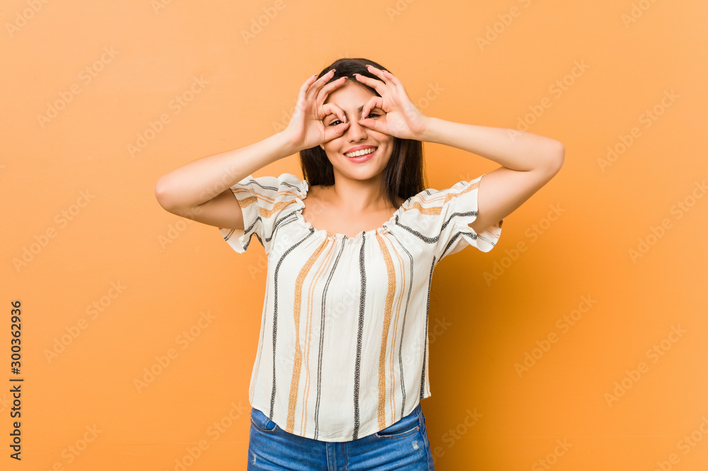Young curvy woman showing okay sign over eyes Young curvy woman showing okay sign over eyes