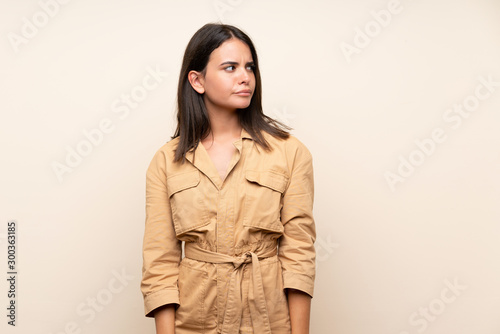 Young girl over isolated background making doubts gesture looking side