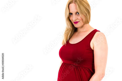 Pregnant woman in red dress holding belly on white background. © _jure