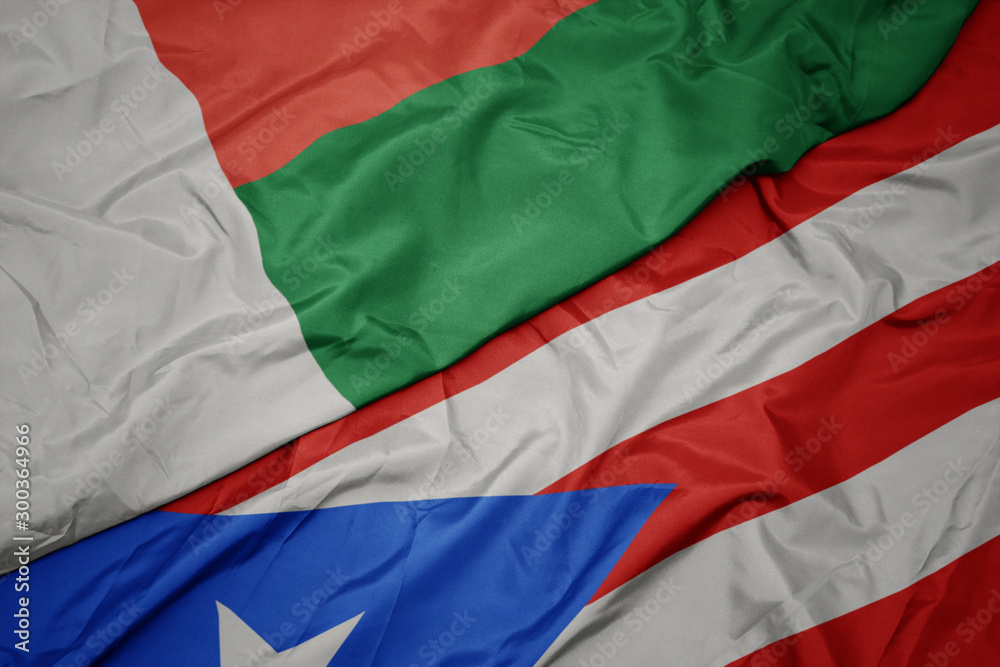 waving colorful flag of puerto rico and national flag of madagascar.