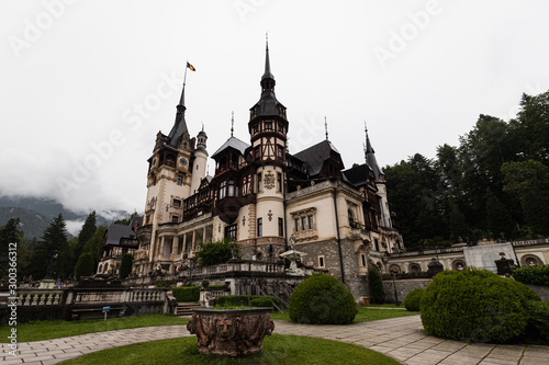 Famous Castle Peles in Sinaia as shot during a rainy day with moody sky and rolling fog (Sinaia, Romania, Europe)